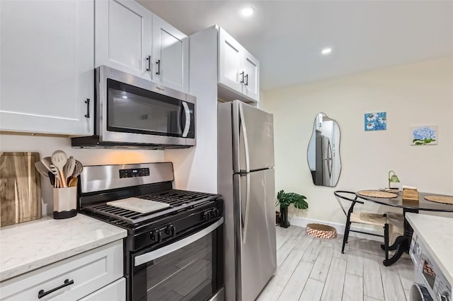 1200 E 52nd St Unit 108, Austin, TX 78723 - kitchen with appliances with stainless steel finishes, light wood-style flooring, light stone counters, white cabinets, and recessed lighting
