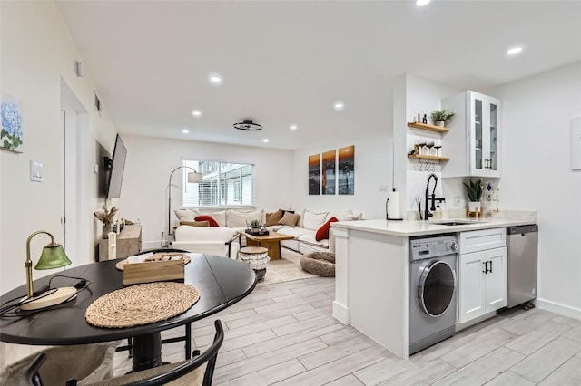 kitchen featuring washer / clothes dryer, white cabinetry, dishwasher, and sink