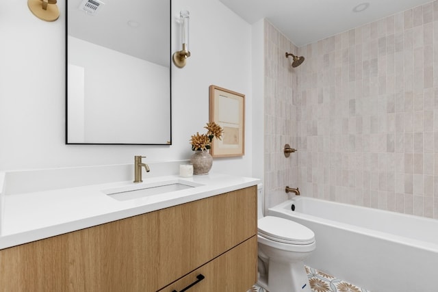 full bathroom featuring tiled shower / bath, vanity, and toilet