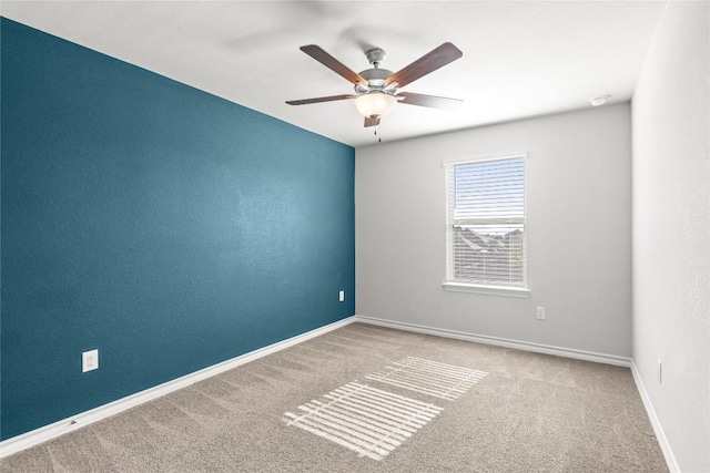 carpeted spare room featuring ceiling fan and baseboards