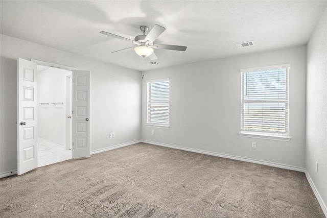 carpeted empty room featuring visible vents, ceiling fan, and baseboards