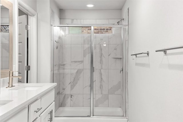 bathroom featuring double vanity, a marble finish shower, and a sink