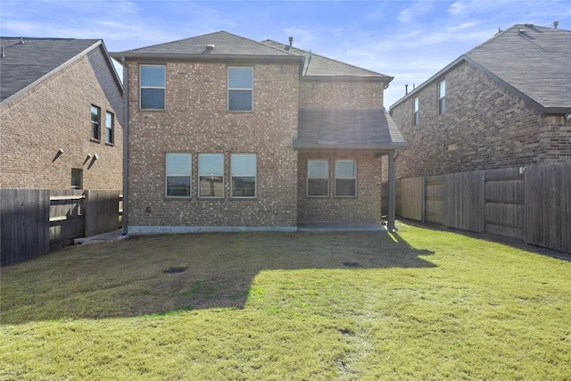 back of house with brick siding, a lawn, a shingled roof, and a fenced backyard