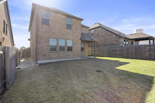 back of house featuring brick siding, a fenced backyard, and a yard