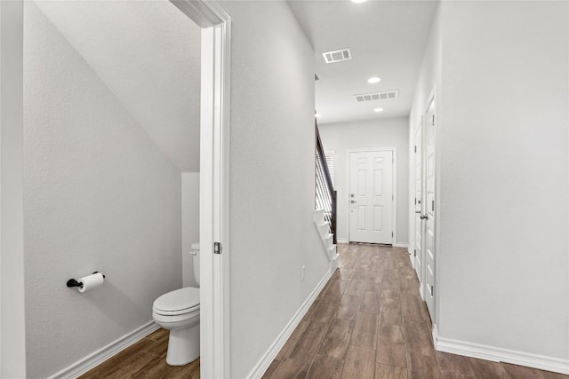 bathroom featuring toilet, wood finished floors, visible vents, and baseboards