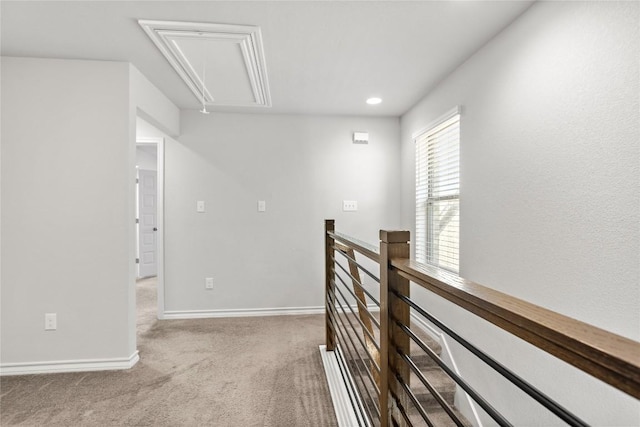 corridor featuring attic access, baseboards, carpet floors, and an upstairs landing