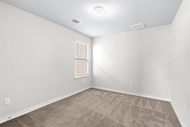 carpeted spare room featuring a textured ceiling, visible vents, and baseboards