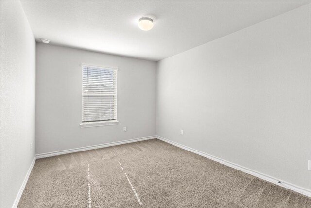 carpeted empty room featuring baseboards