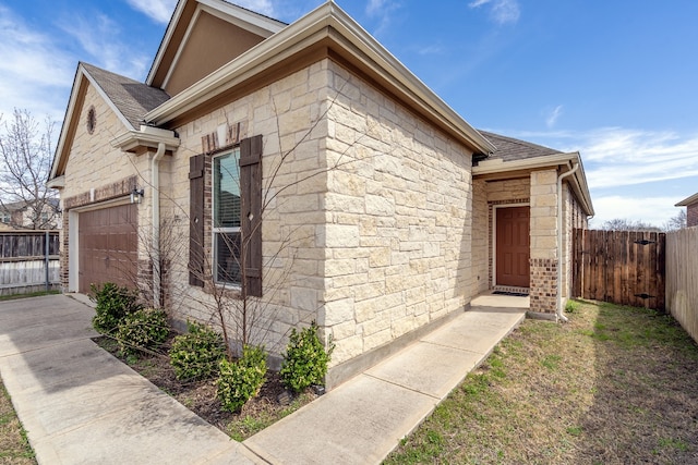 view of side of property featuring a garage, fence, and stone siding