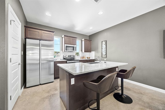 4067 Outpost Trce, Lago Vista, TX 78645 - kitchen with stainless steel appliances, backsplash, a breakfast bar, a center island with sink, and light stone countertops