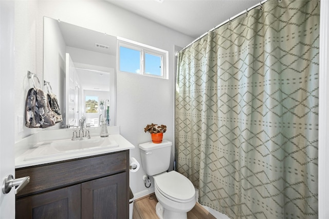 bathroom with hardwood / wood-style flooring, vanity, walk in shower, and toilet