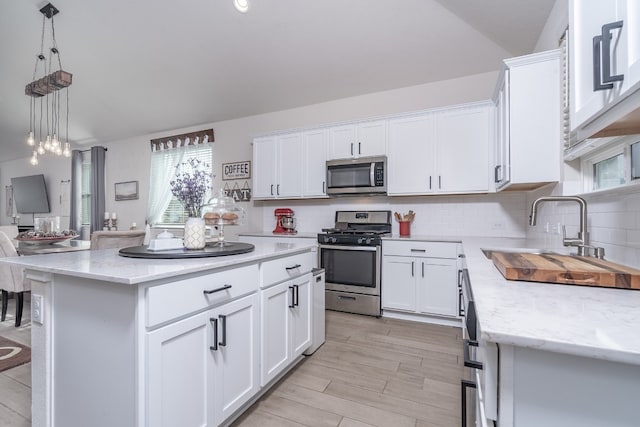 kitchen with white cabinetry, stainless steel appliances, sink, and a kitchen island