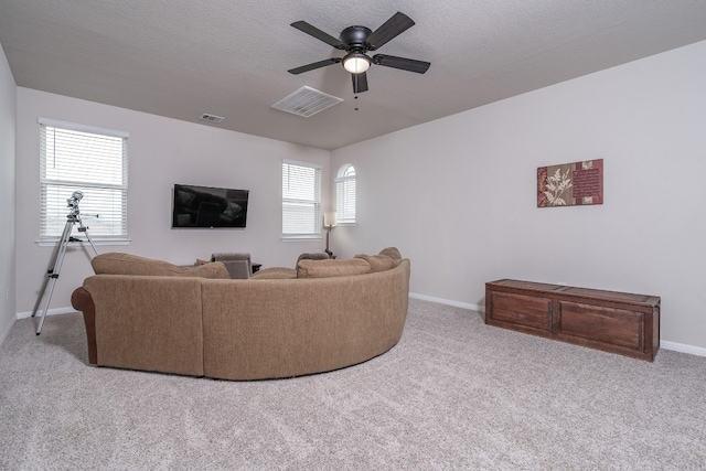 carpeted living room featuring ceiling fan, plenty of natural light, and a textured ceiling