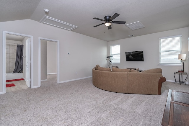 living room with ceiling fan, vaulted ceiling, light carpet, and a textured ceiling