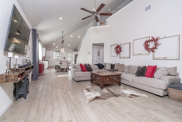 living room with light hardwood / wood-style flooring, high vaulted ceiling, and ceiling fan