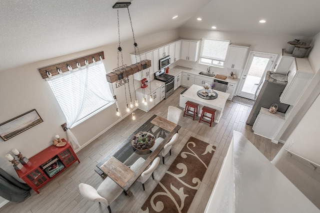 living room featuring lofted ceiling, sink, and light wood-type flooring