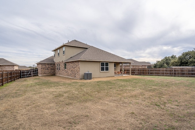 rear view of property with central AC, a patio, and a lawn