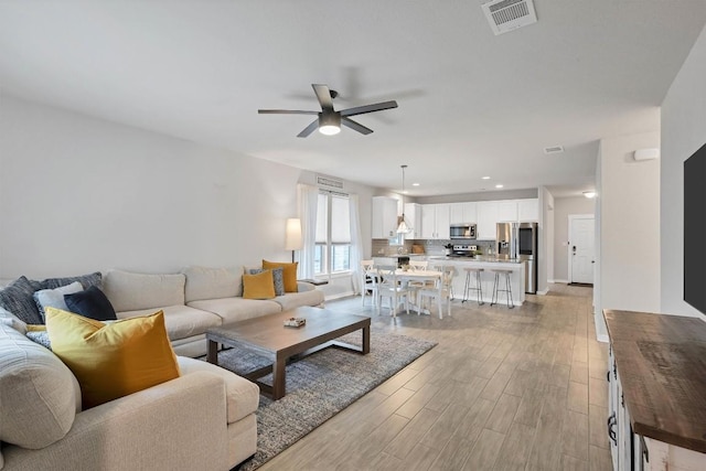 living room with ceiling fan and light wood-type flooring