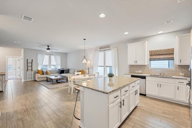 kitchen with sink, white cabinetry, a center island, dishwasher, and pendant lighting