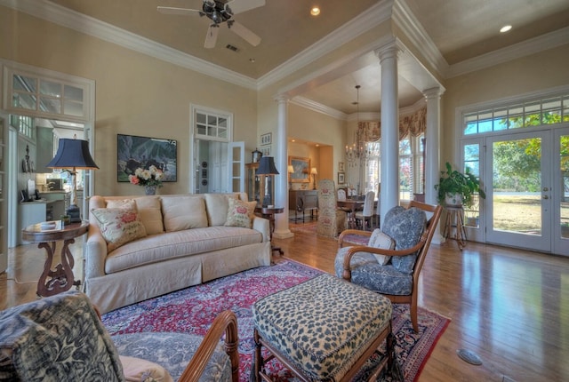 living room with decorative columns, ornamental molding, ceiling fan with notable chandelier, and hardwood / wood-style floors