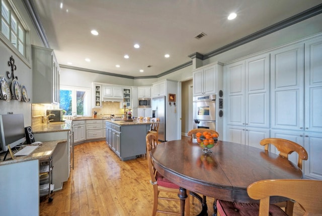 kitchen with backsplash, light hardwood / wood-style flooring, white cabinets, and a kitchen island