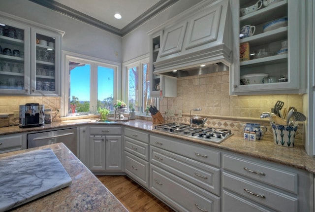 kitchen with sink, light stone counters, ornamental molding, appliances with stainless steel finishes, and dark hardwood / wood-style flooring