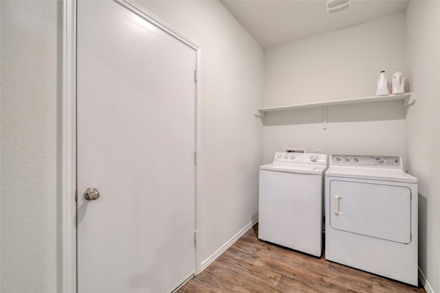 laundry area with separate washer and dryer and light hardwood / wood-style floors