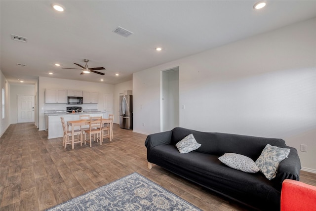 living room featuring light hardwood / wood-style flooring and ceiling fan