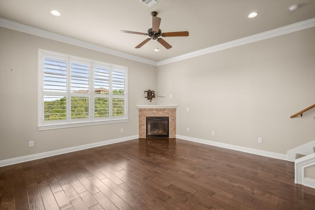 unfurnished living room featuring a tile fireplace, ornamental molding, ceiling fan, and dark hardwood / wood-style flooring