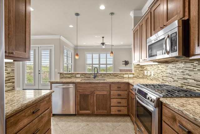 kitchen featuring pendant lighting, sink, light stone counters, kitchen peninsula, and stainless steel appliances