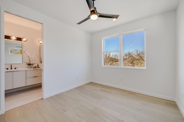 unfurnished bedroom featuring ceiling fan, sink, light hardwood / wood-style floors, and ensuite bath