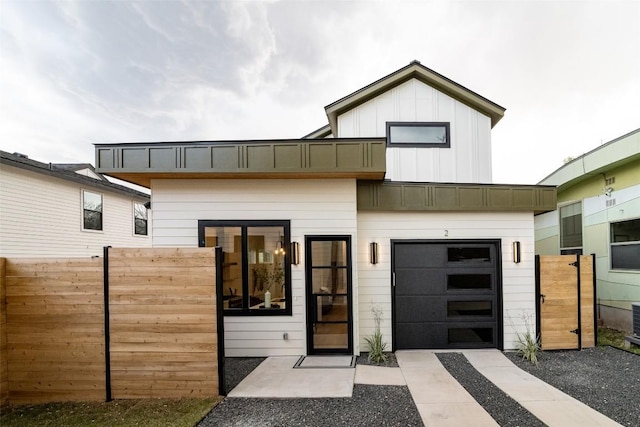 view of front of property featuring board and batten siding, concrete driveway, and fence