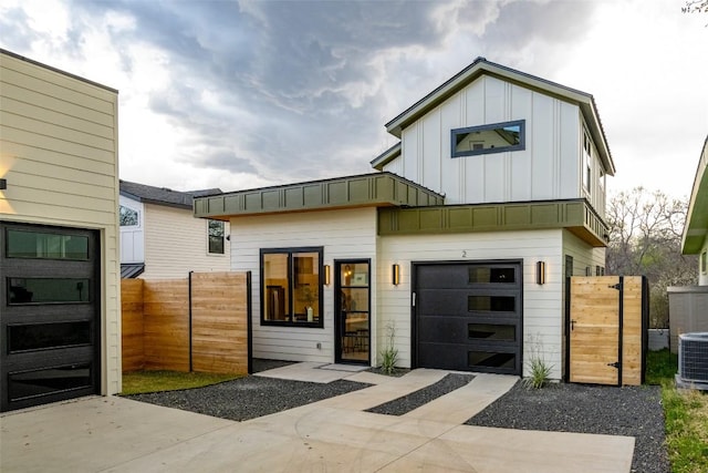 view of front facade with board and batten siding, fence, a garage, driveway, and a gate