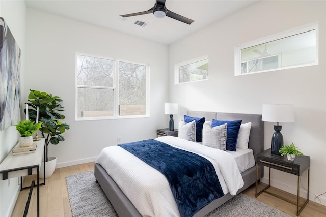 bedroom with visible vents, a ceiling fan, baseboards, and wood finished floors