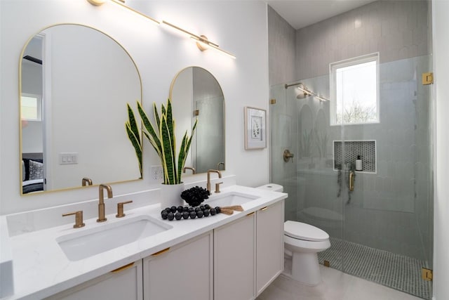 bathroom featuring a sink, toilet, double vanity, and a shower stall