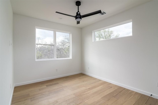 empty room with visible vents, light wood-style flooring, baseboards, and a ceiling fan