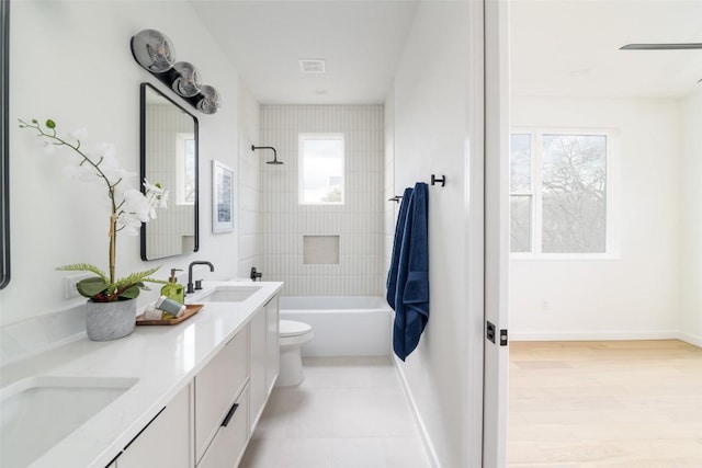 bathroom featuring a wealth of natural light, baseboards, toilet, and a sink