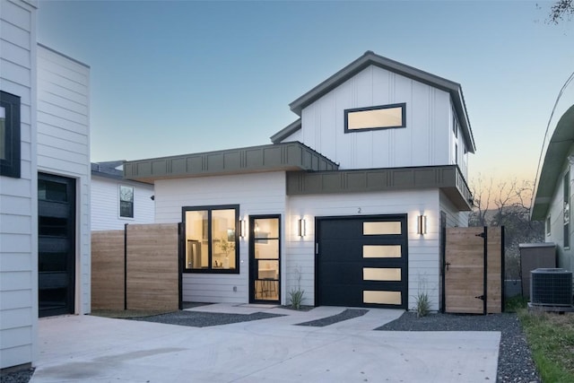 view of front of home with board and batten siding, fence, central AC, a garage, and driveway