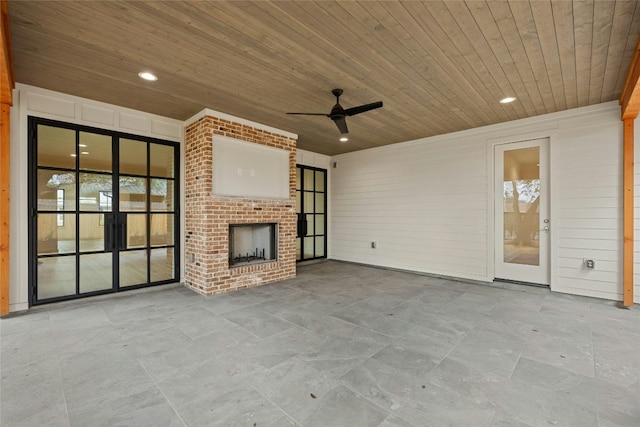 unfurnished living room with an outdoor brick fireplace, ceiling fan, and wooden ceiling