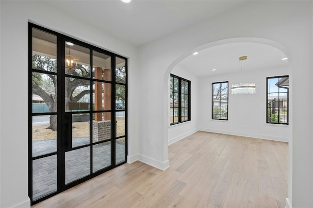 empty room with an inviting chandelier and light hardwood / wood-style floors