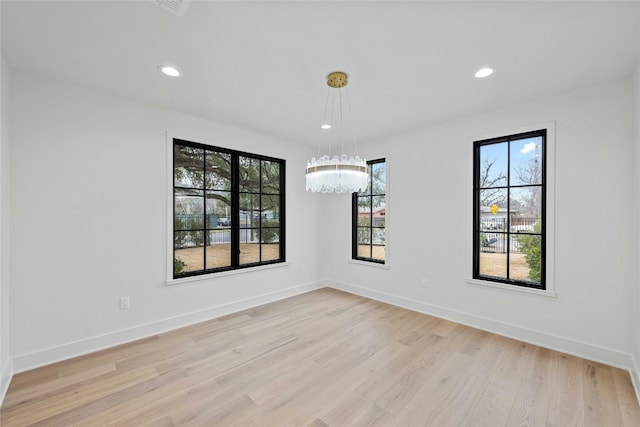 unfurnished room with an inviting chandelier and light hardwood / wood-style flooring