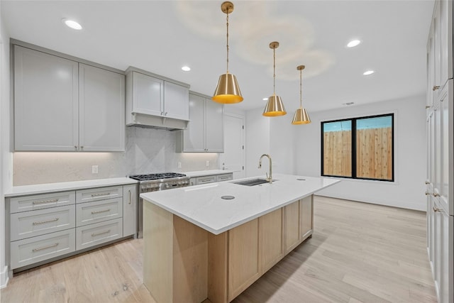 3008 W 50th St, Austin, TX 78731 - kitchen featuring light wood finished floors, tasteful backsplash, recessed lighting, a kitchen island with sink, and high end range
