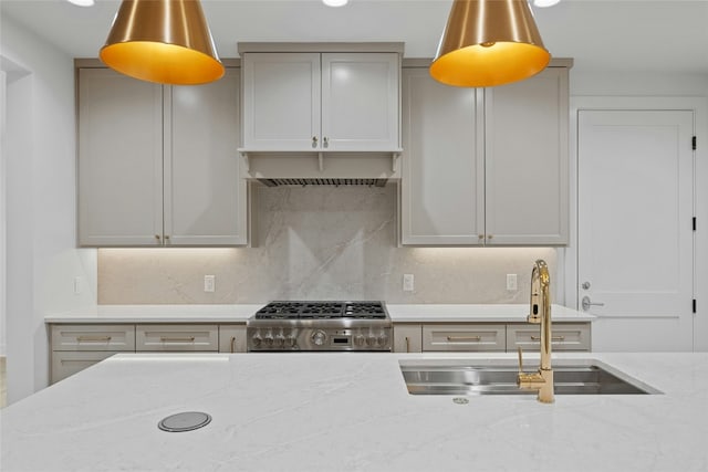 kitchen featuring gray cabinets, light stone countertops, sink, and range