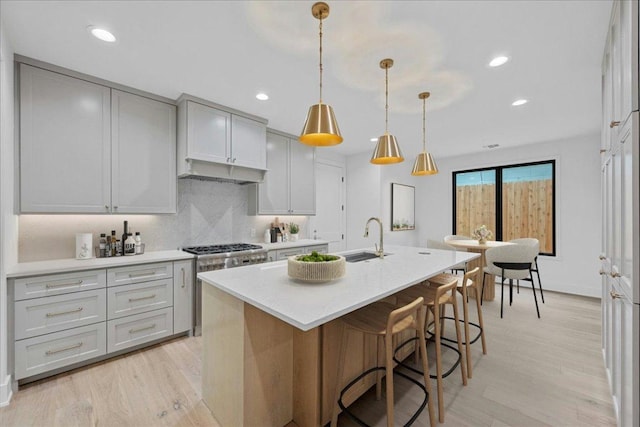 3008 W 50th St, Austin, TX 78731 - kitchen with decorative backsplash, an island with sink, light countertops, light wood-type flooring, and recessed lighting