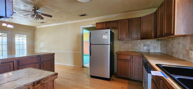 2810 Inwood Rd, Temple, TX 76502 - kitchen featuring stainless steel appliances, a ceiling fan, ornamental molding, decorative backsplash, and light wood-style flooring