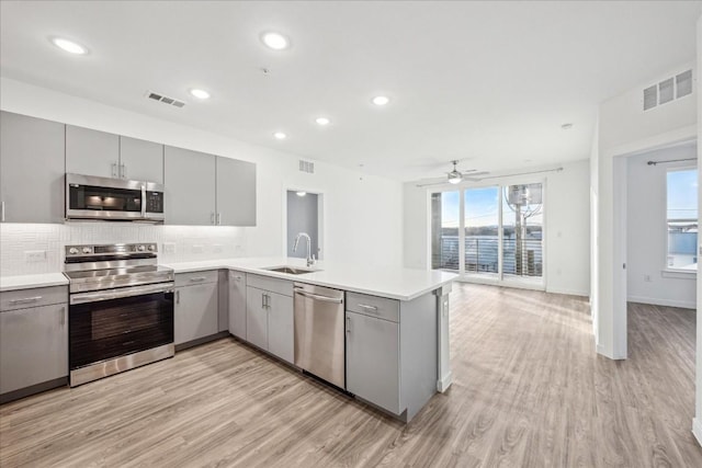 kitchen featuring sink, gray cabinets, stainless steel appliances, and kitchen peninsula