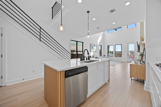 kitchen with pendant lighting, white cabinetry, an island with sink, sink, and stainless steel dishwasher