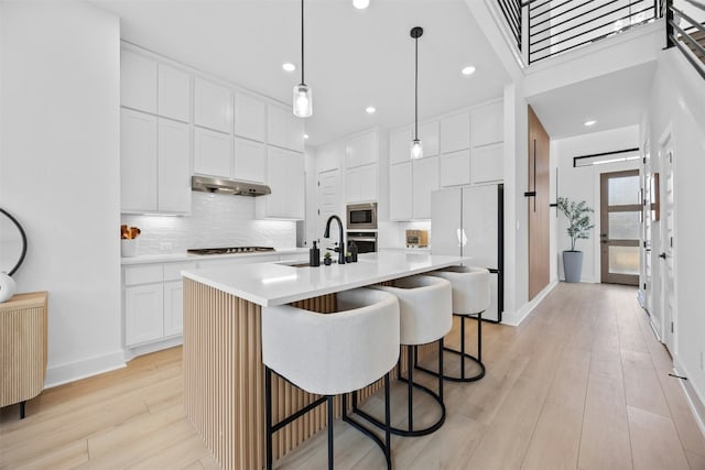 kitchen with white cabinetry, sink, hanging light fixtures, a kitchen island with sink, and stainless steel appliances