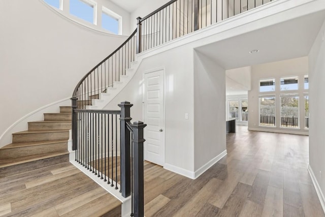 staircase with a towering ceiling and wood-type flooring