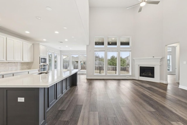 kitchen with sink, plenty of natural light, a spacious island, white cabinets, and built in microwave